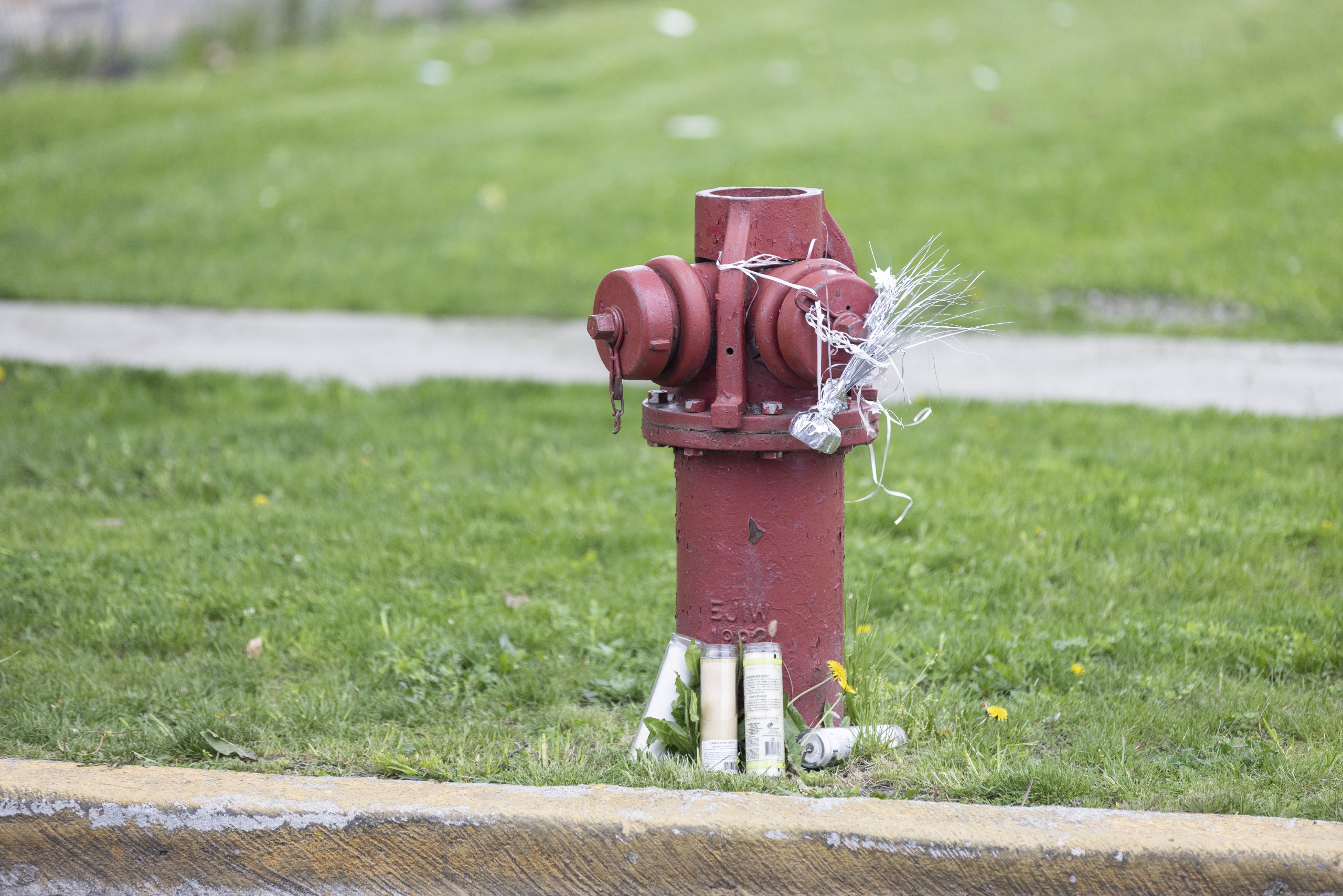 A red fire hydrant serves as a makeshift memorial for Dexter Reed adorned with candles and the remnants of balloons.