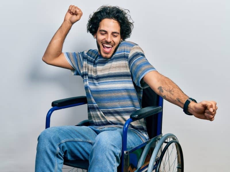 Handsome young Latino man dancing exuberantly in his wheelchair