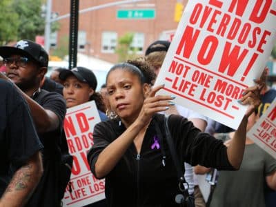 Protesters hold signs reading "End overdose now! Not one more life lost."