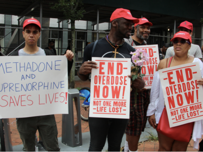 Protesters in New York hold signs that say "Methadone and Buprenorphine saves lives!" and "End overdose now! Now one more life lost."