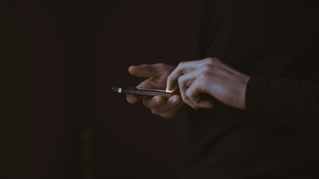 A close-up of hands holding and typing on a cellphone.