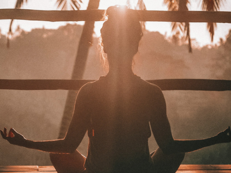A woman sits in meditation outside.