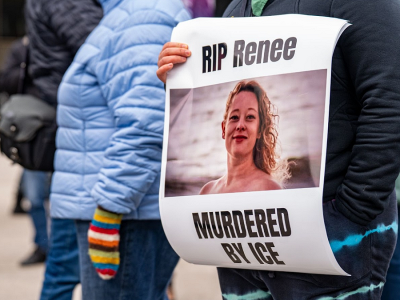 A protester holds a poster with a picture of Renee Good and text that reads "RIP Renee, murdered by ICE"