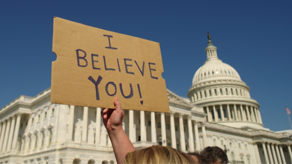 A person holds a sign that reads "I believe you!" outside of the U.S. Capitol building