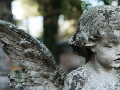 A moss-covered, weathered angel statue in a cemetery