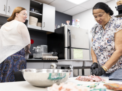 Two women are pictured preparing food in a kitchen.