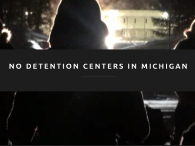 A group of people stand outside at night, their backs turned to the camera. Text over the photo reads "No detention centers in Michigan."