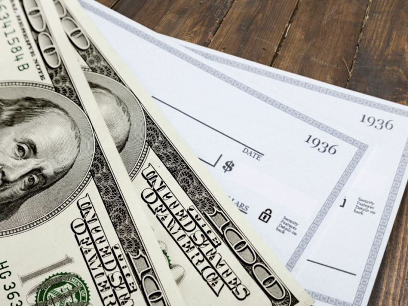 A stack of $100 bills and checks.