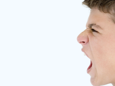 A profile view of a teenage boy yelling angrily