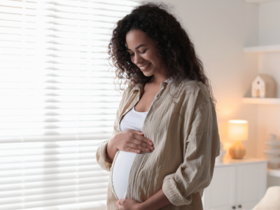 A pregnant woman smiles while holding her belly